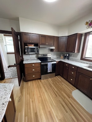 A kitchen with wooden cabinets, a stainless steel oven, a microwave, and a coffee maker.