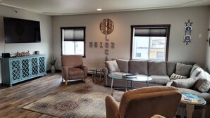 A living room with a sofa, armchair, coffee table, and a cabinet. - Penthouse in the heart of Downtown Fargo with private rooftop patio (Fargo)