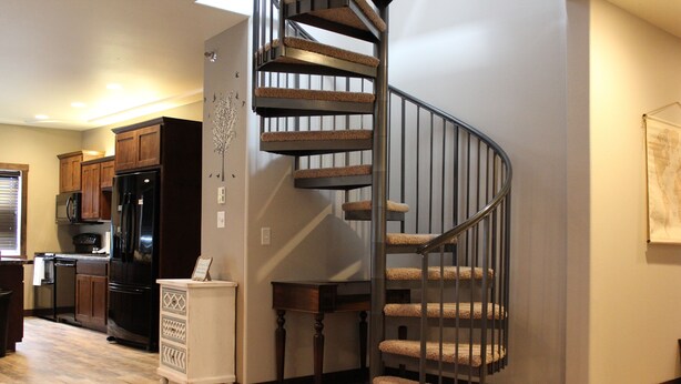 A kitchen with wooden cabinets, a black refrigerator, and a microwave. - Penthouse in the heart of Downtown Fargo with private rooftop patio (Fargo)