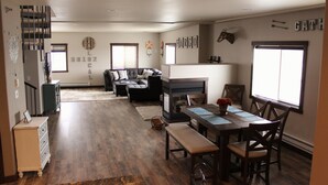 A spacious living room with a fireplace, a dining area with a wooden table and chairs, and a cozy seating area with a sofa and cushions. - Penthouse in the heart of Downtown Fargo with private rooftop patio (Fargo)