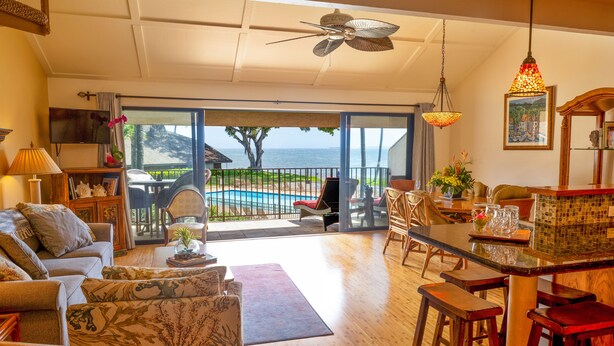 A spacious living room with a view of the ocean, a dining area with bar stools, and a cozy seating area with a fireplace. - Ma'alaea Surf, Unit G9-2BR Beachfront Condo, AC, Wi-Fi, TV, Pool, Kitchen (Kihei)