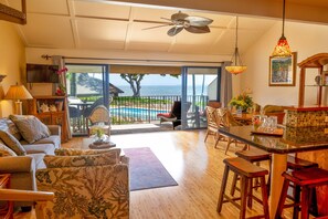 A spacious living room with a view of the ocean, a dining area with bar stools, and a cozy seating area with a fireplace.