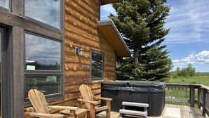 Une terrasse en bois avec des fauteuils Adirondack et un jacuzzi.