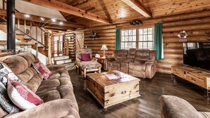 A log cabin interior with a wooden staircase, a sofa, armchairs, a wooden chest, and a fireplace. - CIDER CABIN - Brown County's Finest Log Cabin (Nashville)