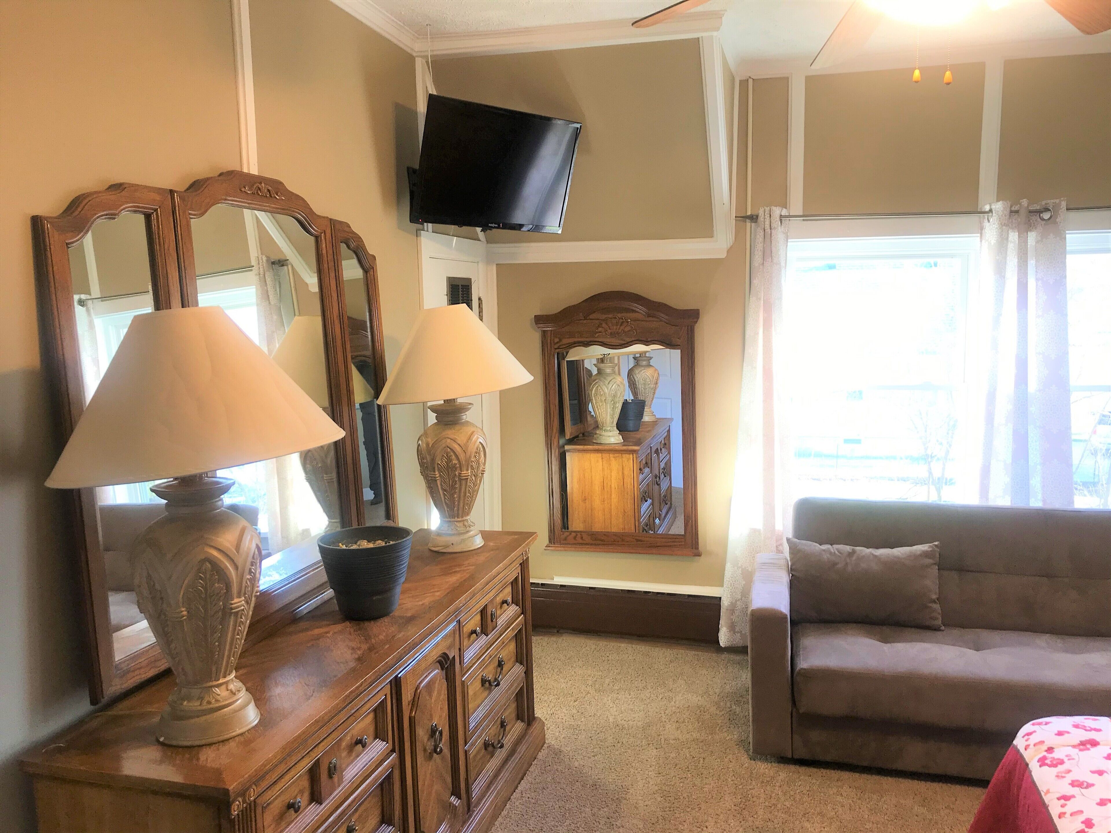 A living room with a wooden cabinet, two lamps, a television, and a couch.