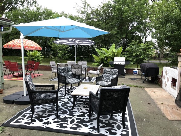 An outdoor patio area with a dining table, chairs, and a blue umbrella.