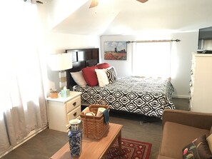 A bedroom with a bed, bedside table, lamp, and a painting on the wall.