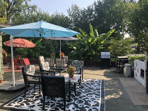 A patio area with outdoor furniture, a grill, and potted plants.