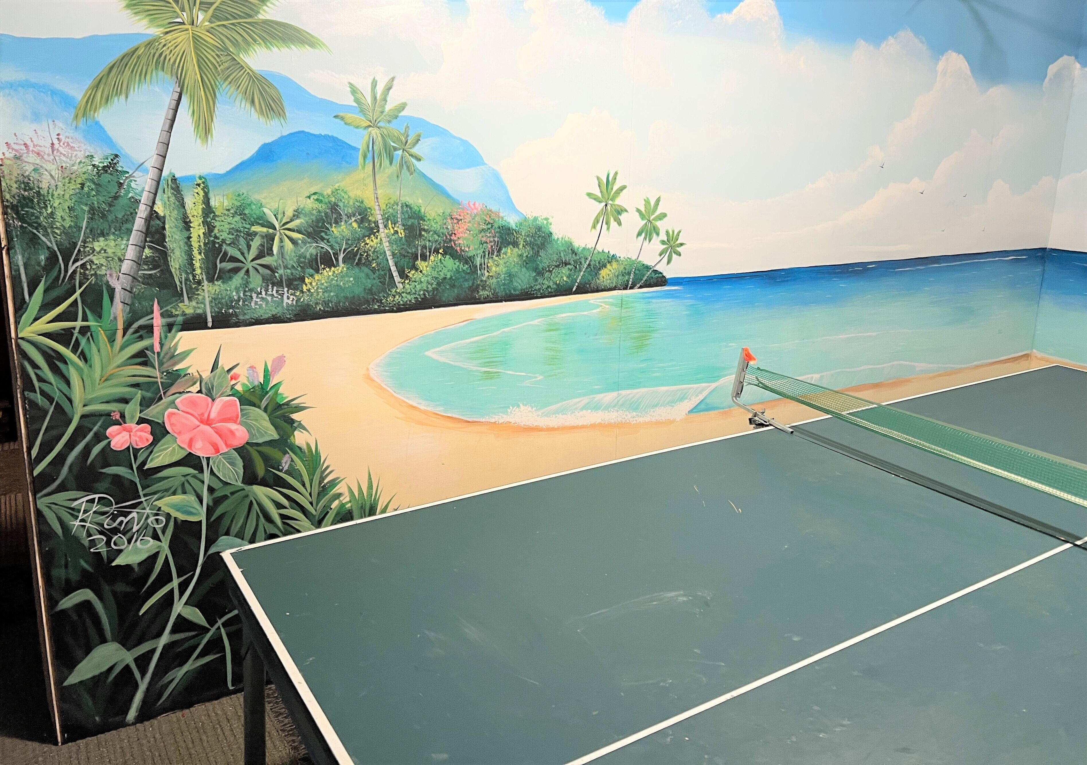 A tennis court with a mural of a beach scene.