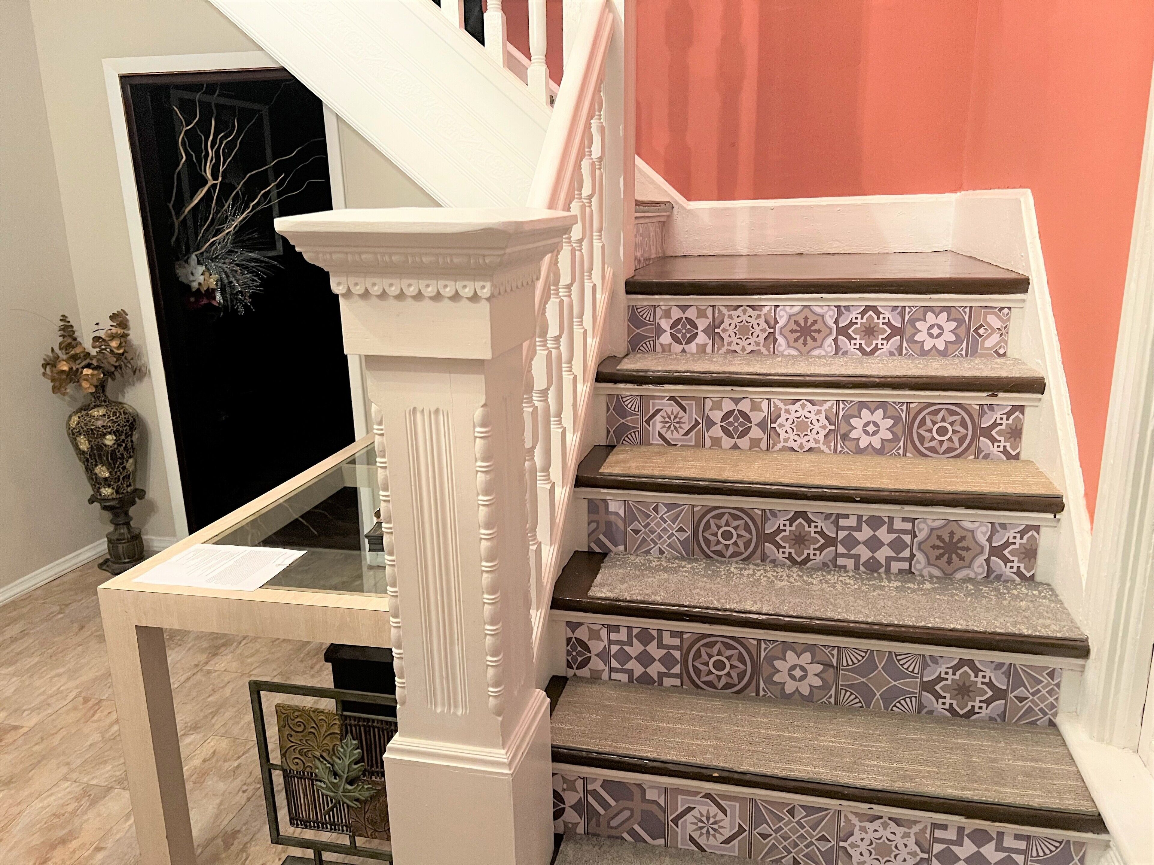Un escalier orné de balustres blancs et de carreaux aux motifs décoratifs.