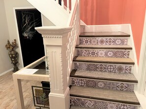 A staircase with ornate white balusters and patterned tiles.