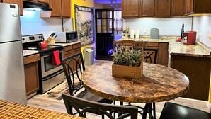 Une cuisine dotée de meubles en bois, d’un réfrigérateur en acier inoxydable, d’un four à micro-ondes, d’une cuisinière et d’une table à manger avec des chaises.