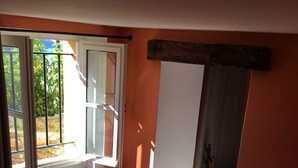 Een kamer met een bed, een raam en een deur die uitkomt op een balkon.