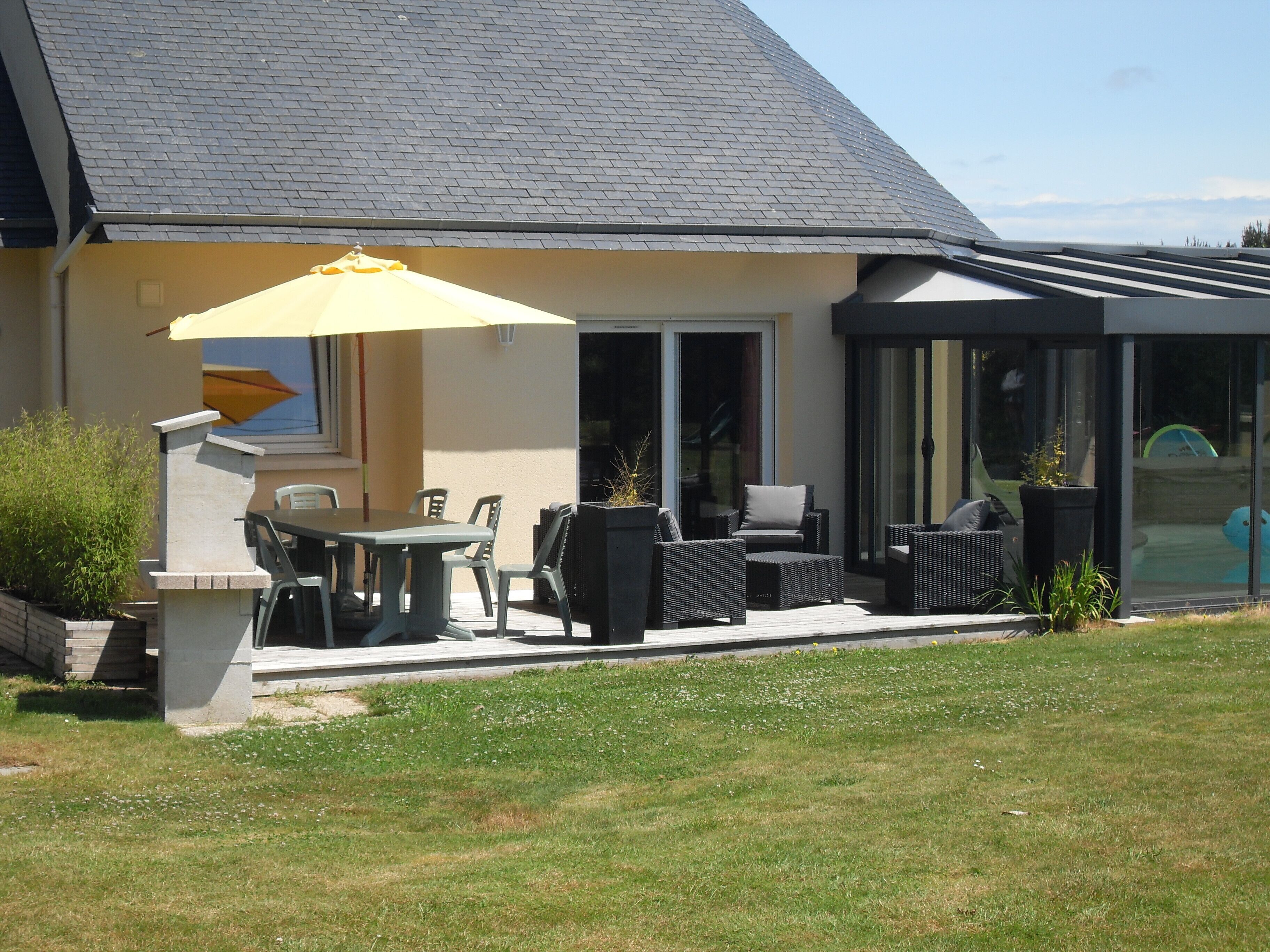 A house with a patio area featuring outdoor furniture and a yellow umbrella.