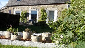 A stone house with a sloped roof, two windows, and a small garden with potted plants. - In a "fisherman's house" spirit, between Finistère and the pink granite coast (Plouezoc'h)