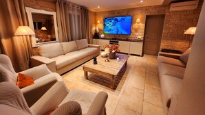 Una sala de estar moderna con un sofá, sillones, una mesa de centro y un televisor instalado en una pared de piedra.