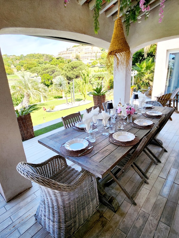 A dining area with a view of a lush garden and distant buildings.