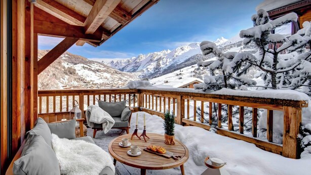 A wooden deck with a view of snow-covered mountains. - Chalet Timan - ski-in ski-out break for 8, spa & views - OVO Network (La Clusaz)