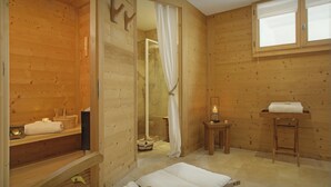 A wooden cabin with a shower, a bench, and a small table with a candle. - Chalet Timan - ski-in ski-out break for 8, spa & views - OVO Network (La Clusaz)