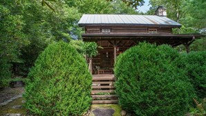A rustic cabin with a wooden exterior, a porch, and a chimney. - Aunt Babbies Cabin in Pisgah Forest (Pisgah Forest)