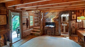 A log cabin interior with a wooden staircase, a desk, a chair, a sink, and a window. - Aunt Babbies Cabin in Pisgah Forest (Pisgah Forest)