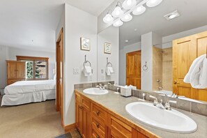 Un baño moderno con dos lavamanos, un espejo grande y armarios de madera.