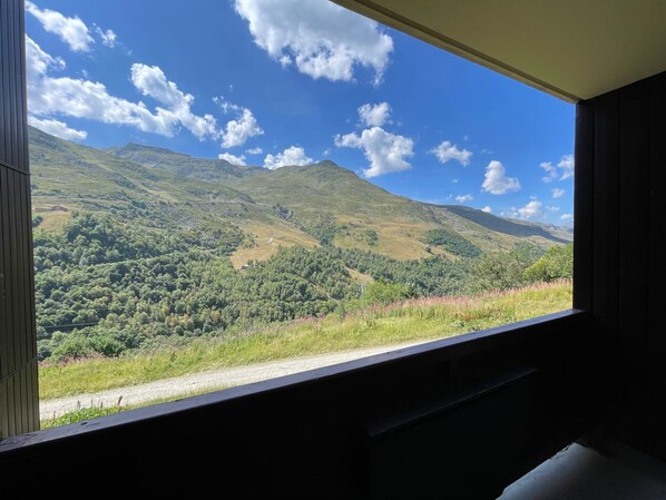 A room with a large window offering a view of a mountainous landscape.