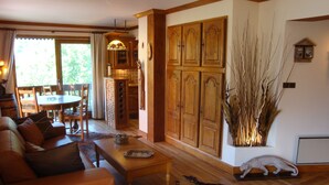 Un accogliente soggiorno con divano, tavolo da pranzo e camino. Si nota un ampio mobile in legno e una pianta decorativa.