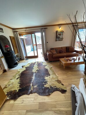 Ein Wohnzimmer mit großem Teppich, einer Couch, einem Couchtisch und einem Kamin.