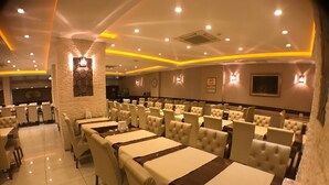Un restaurant doté de nombreuses tables et de coins repas, d’un mur décoratif en pierre et d’un éclairage encastré au plafond.