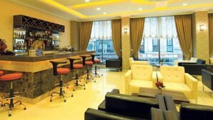 Un hall d’hôtel doté d’un bar, de coins salon et de grandes fenêtres.