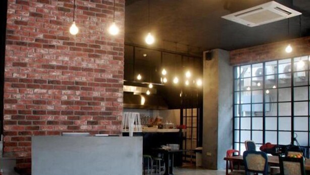 Un vaste espace dédié à la salle à manger, avec un mur en briques, une longue table et des chaises.