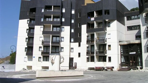 Un moderno edificio a più piani con balconi e un cortile centrale.