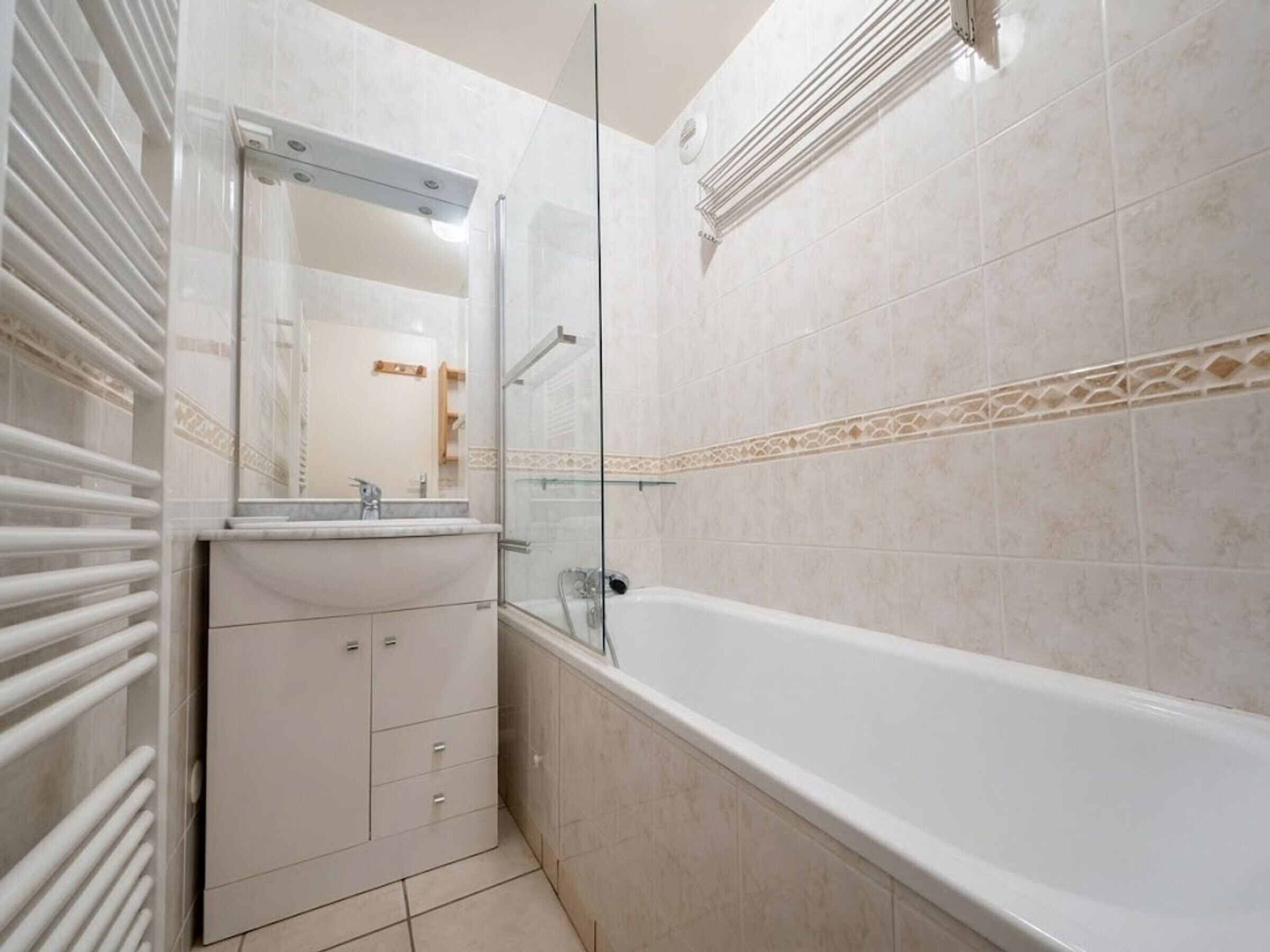 A bathroom with a bathtub, a glass shower enclosure, and a vanity with a mirror.
