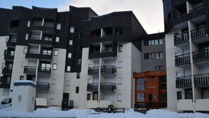 Un edificio residenziale a più piani con balconi e terreno innevato.