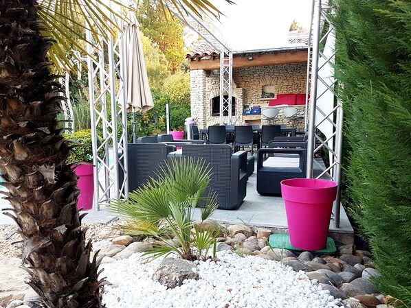 Un patio al aire libre con mobiliario de mimbre, un muro de piedra y una piscina.