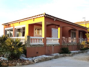 Una casa de dos pisos con fachada roja, marcos de ventana blancos y cimientos de piedra.
