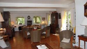 A spacious living room with a dining area, large windows, and a fireplace.