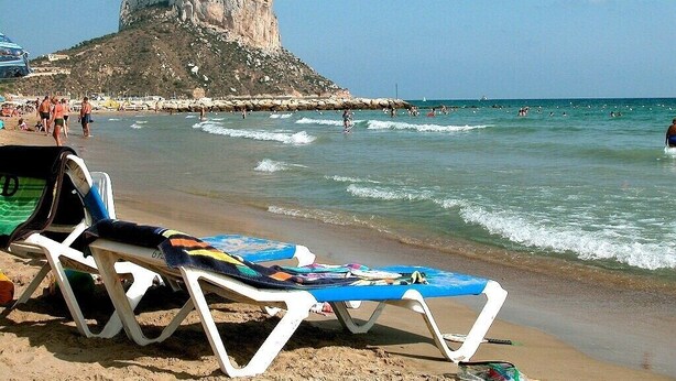 A beach with lounge chairs, a rocky cliff, and the sea. - Villa Robert. Smart detached Villa with communal pool and fully fenced garden (Calpe)