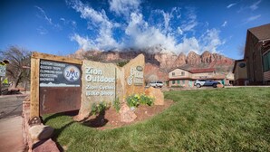 A sign for Zion Outdoor and Pizza & Noodles with a mountain backdrop.