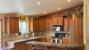 A kitchen with wooden cabinets, a granite countertop, a stainless steel stove, and a refrigerator.