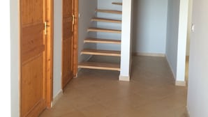 A hallway with wooden doors, a staircase, and a tiled floor.