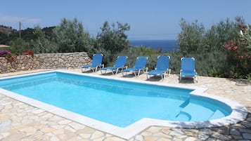 Relax by the pool surrounded by lush greenery and a stunning sea view.