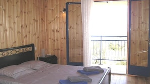 A wooden cabin bedroom with a bed, nightstand, and a balcony door.