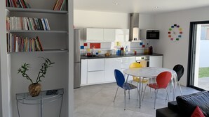 Eine moderne Küche mit weißen Schränken, einer farbenfrohen Spritzschutzleiste und einem Essbereich mit einem runden Tisch und Stühlen.