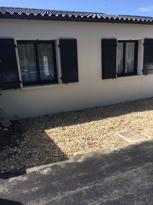 A building with a tiled roof, three windows with shutters, and a gravel driveway. - Charming new house in La Rochelle (La Rochelle)