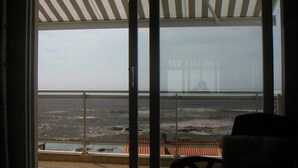 Une pièce dotée d’une grande porte-fenêtre coulissante donnant sur un balcon avec vue sur la plage.