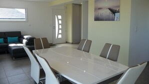 Une salle de réunion moderne, dotée d’une grande table et de chaises, d’un canapé avec des coussins et d’une porte dont le design de fenêtre est unique.