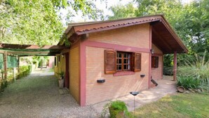 A small brick building with a sloped roof, wooden shutters, and a covered porch area.