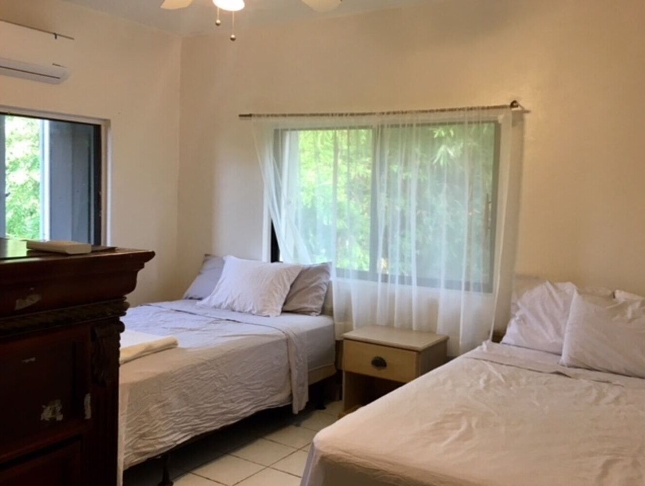 Une chambre avec deux lits, une table de chevet et une commode.